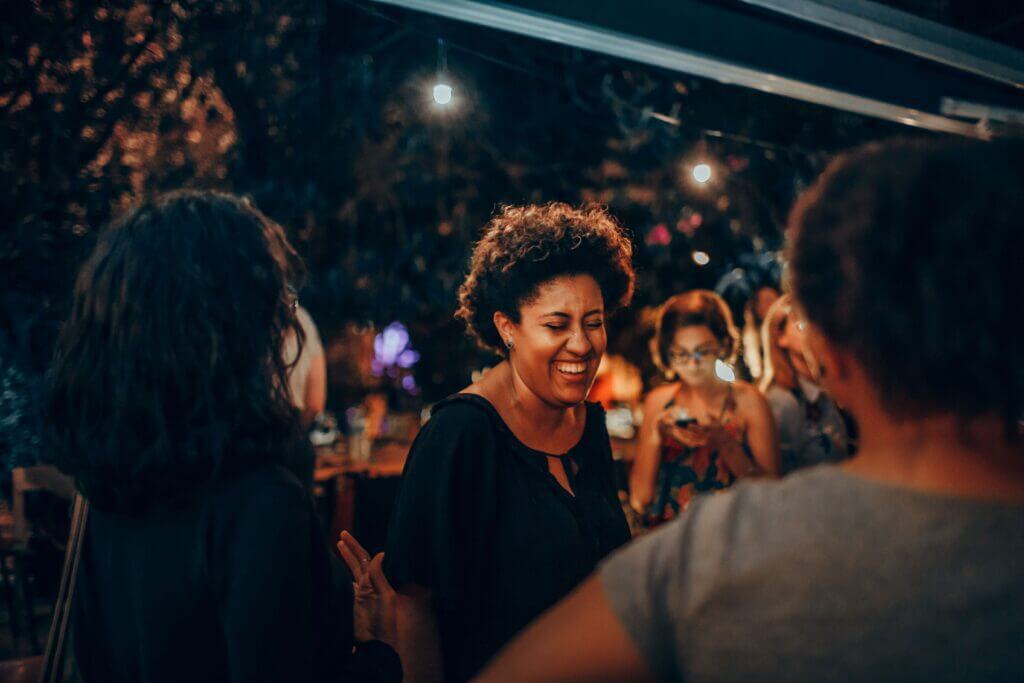 Woman laughing and enjoying time with friends during a social gathering, representing confidence, resilience, and personal growth during while experiencing the benefits of perimenopause.