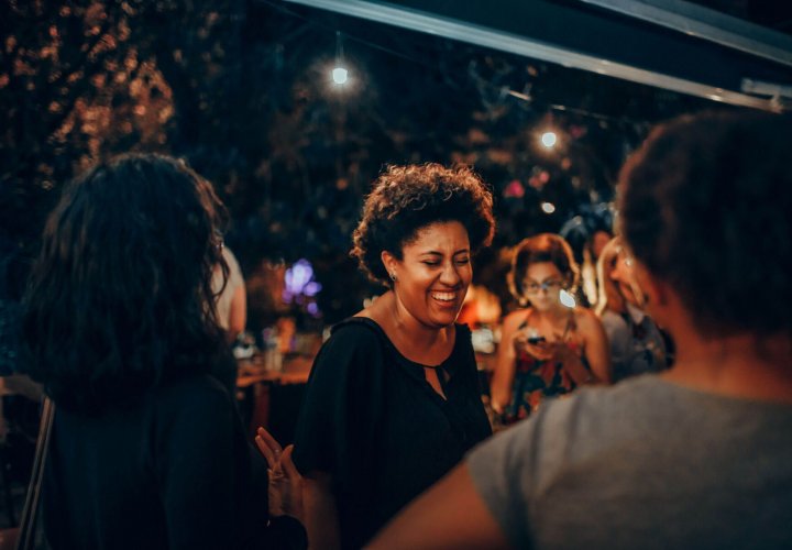 Woman laughing and enjoying time with friends during a social gathering, representing confidence, resilience, and personal growth during while experiencing the benefits of perimenopause.